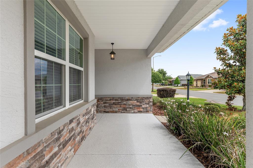 A covered front porch features a concrete floor, stone veneer siding, and a hanging lantern — 9326 SW 97TH CIRCLE, OCALA, FL