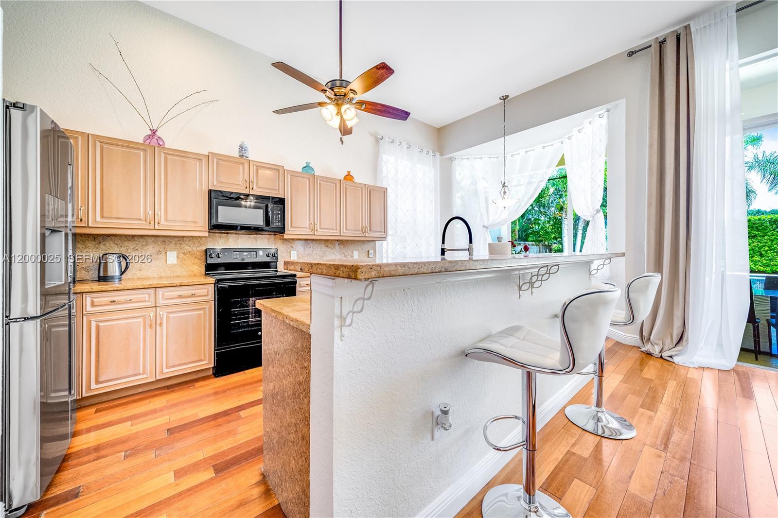 A kitchen features light wood cabinets, black appliances, a granite breakfast bar, and hardwood floors — 1241 S 13th Ave, Hollywood FL 33019, HOLLYWOOD, FL