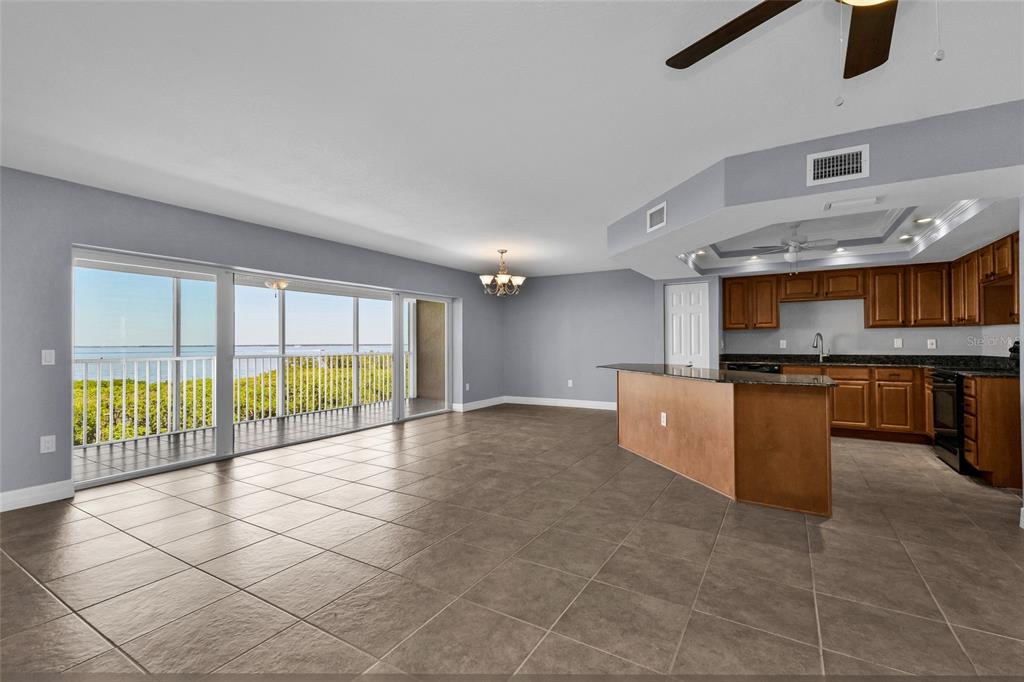An open-concept kitchen and living area with tile floors, wooden cabinets, and a waterfront balcony — 101 N MARION COURT UNIT 213, PUNTA GORDA, FL