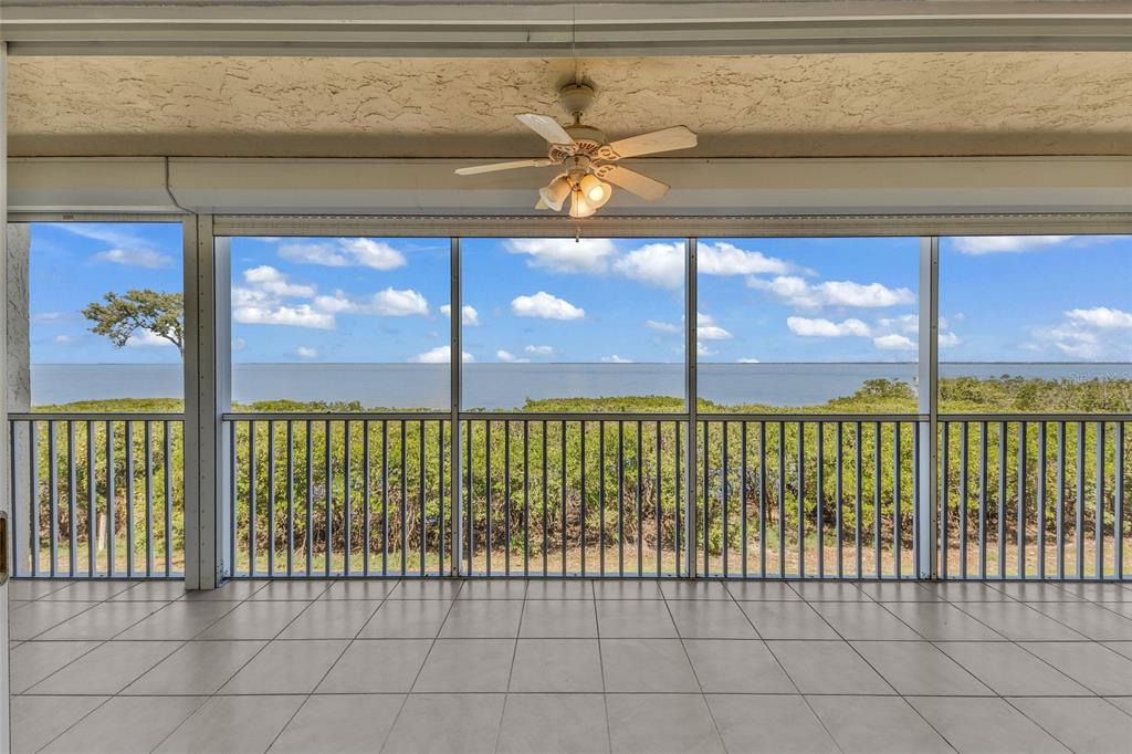 A tiled, screened-in balcony overlooks a body of water and lush green vegetation — 101 N MARION COURT UNIT 213, PUNTA GORDA, FL