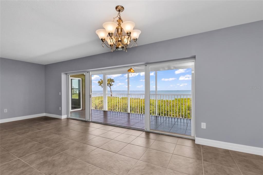 A room with tile flooring and a chandelier features large sliding doors opening to a balcony — 101 N MARION COURT UNIT 213, PUNTA GORDA, FL
