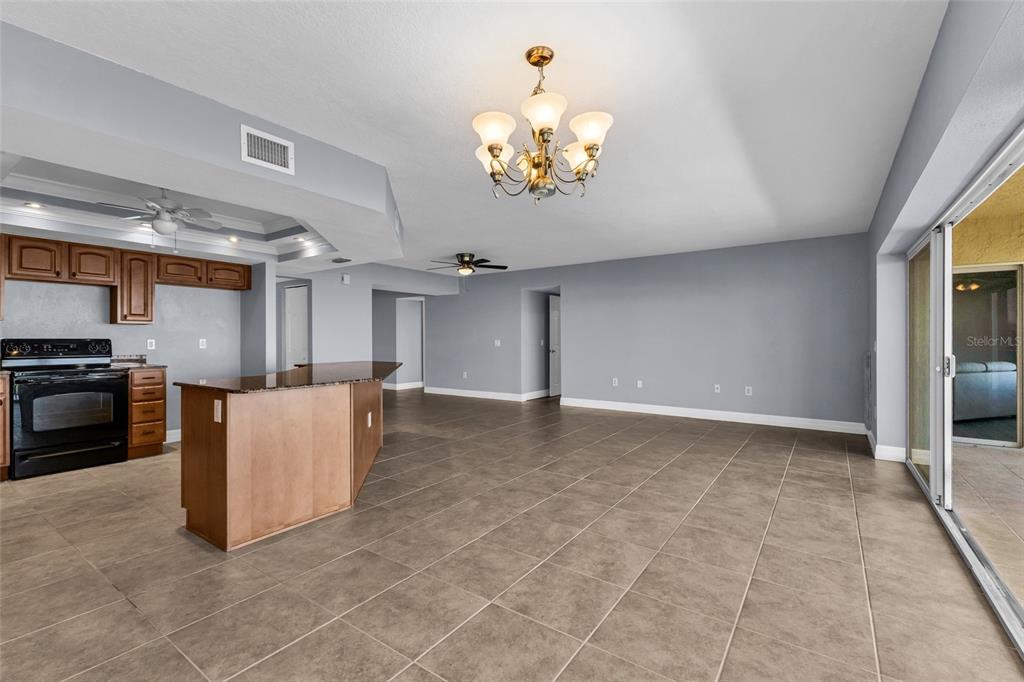 An open-concept kitchen and living area with tile flooring, a central island, and chandelier lighting — 101 N MARION COURT UNIT 213, PUNTA GORDA, FL