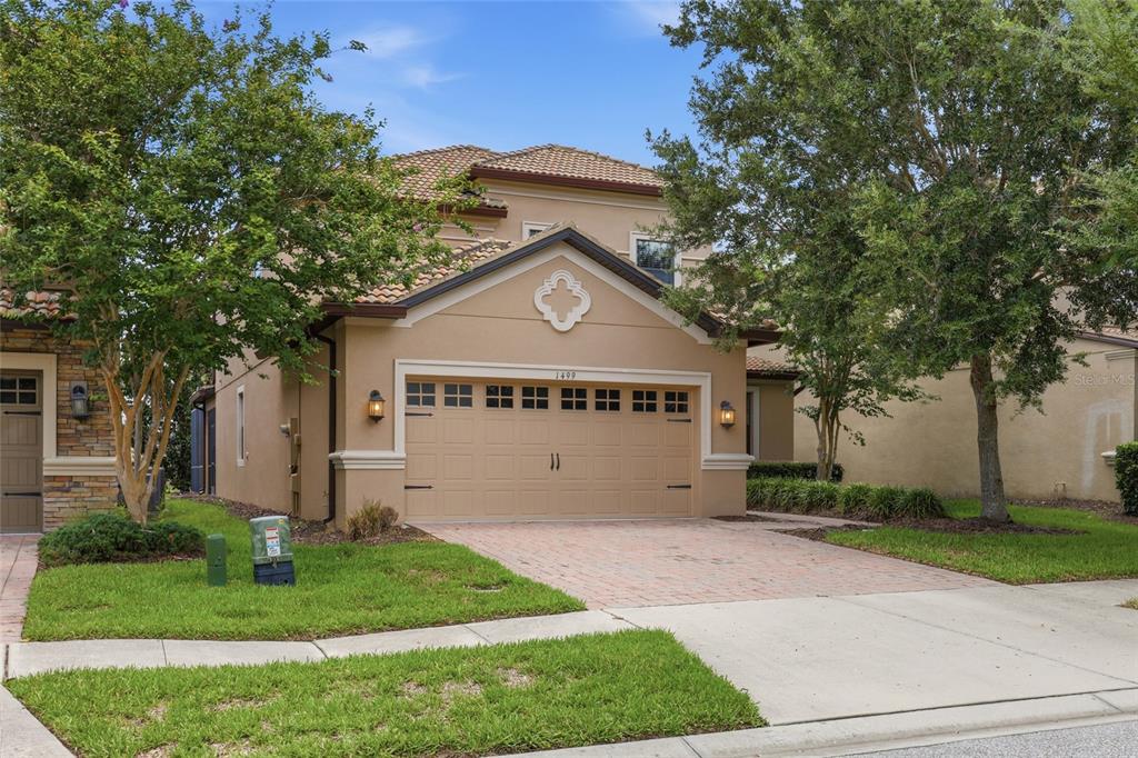 A two-story house with a tan stucco exterior, a tile roof, and a two-car garage — 1499 ROLLING FAIRWAY DRIVE, DAVENPORT, FL