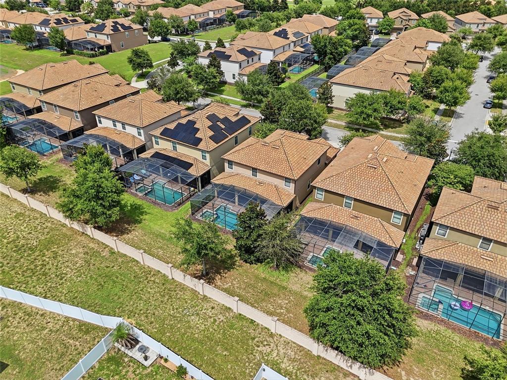 An aerial view shows several suburban houses with tiled roofs, swimming pools, and screened enclosures — 1499 ROLLING FAIRWAY DRIVE, DAVENPORT, FL