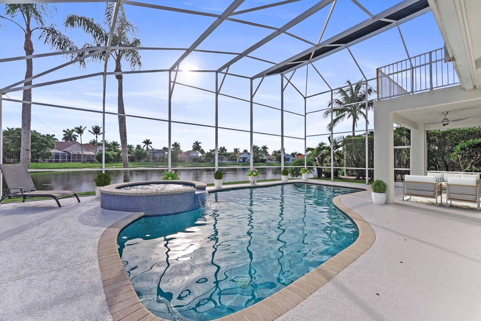 A screened-in pool and spa overlook a lake with palm trees in the background — 19483 Black Olive Lane, Boca Raton FL 33498, BOCA RATON, FL