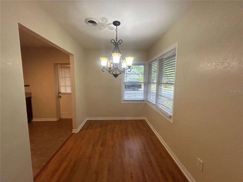 A dining area features wood-look flooring, a chandelier, and windows with white blinds — 2704 NW 1ST AVENUE, GAINESVILLE, FL