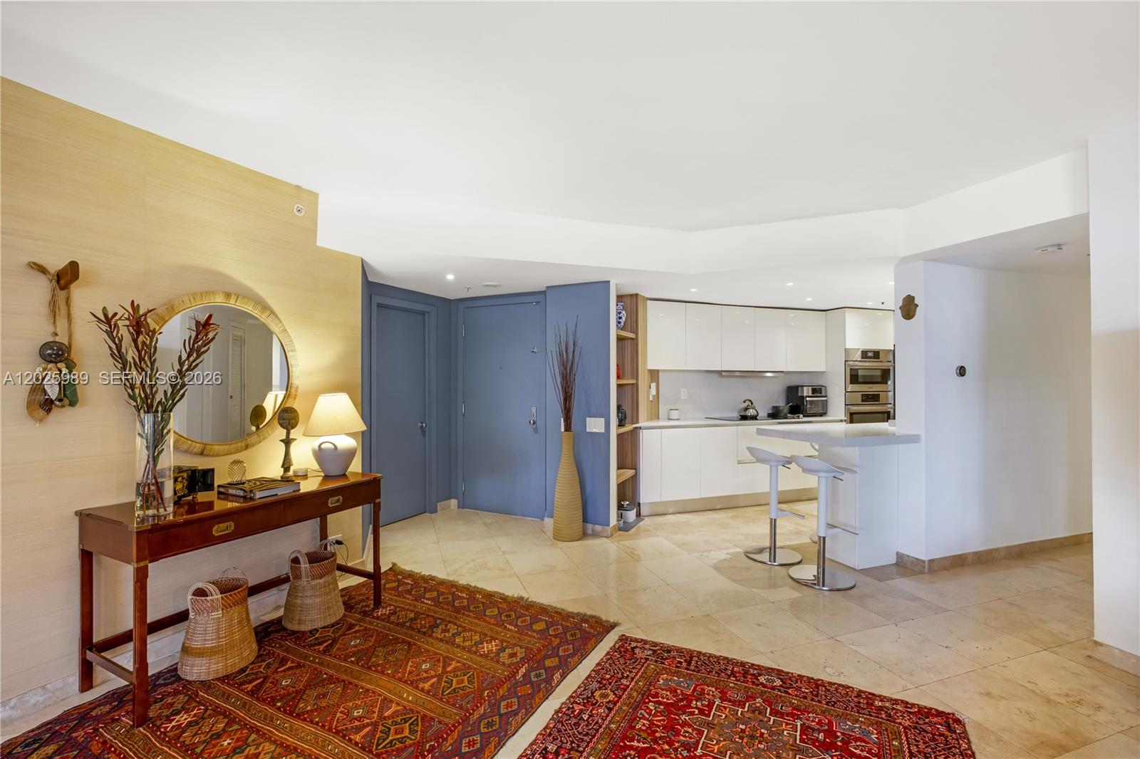 A kitchen with white cabinets and a breakfast bar sits beside a blue-walled entryway — 701 Brickell Key Blvd # 512, Miami FL 33131, MIAMI, FL