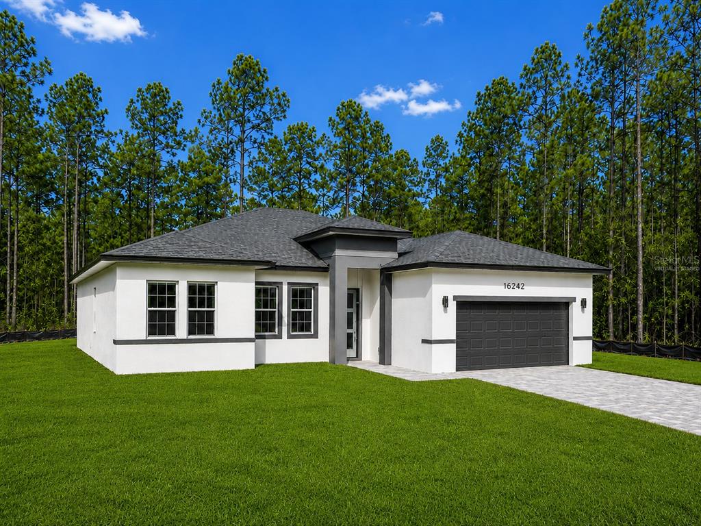 A single-story house with white stucco walls, a dark gray roof, and a two-car garage — 16242 SW 28TH TERRACE, OCALA, FL