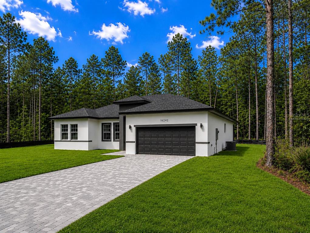 A modern, white single-story house with a dark garage and roof sits on a lawn — 16242 SW 28TH TERRACE, OCALA, FL