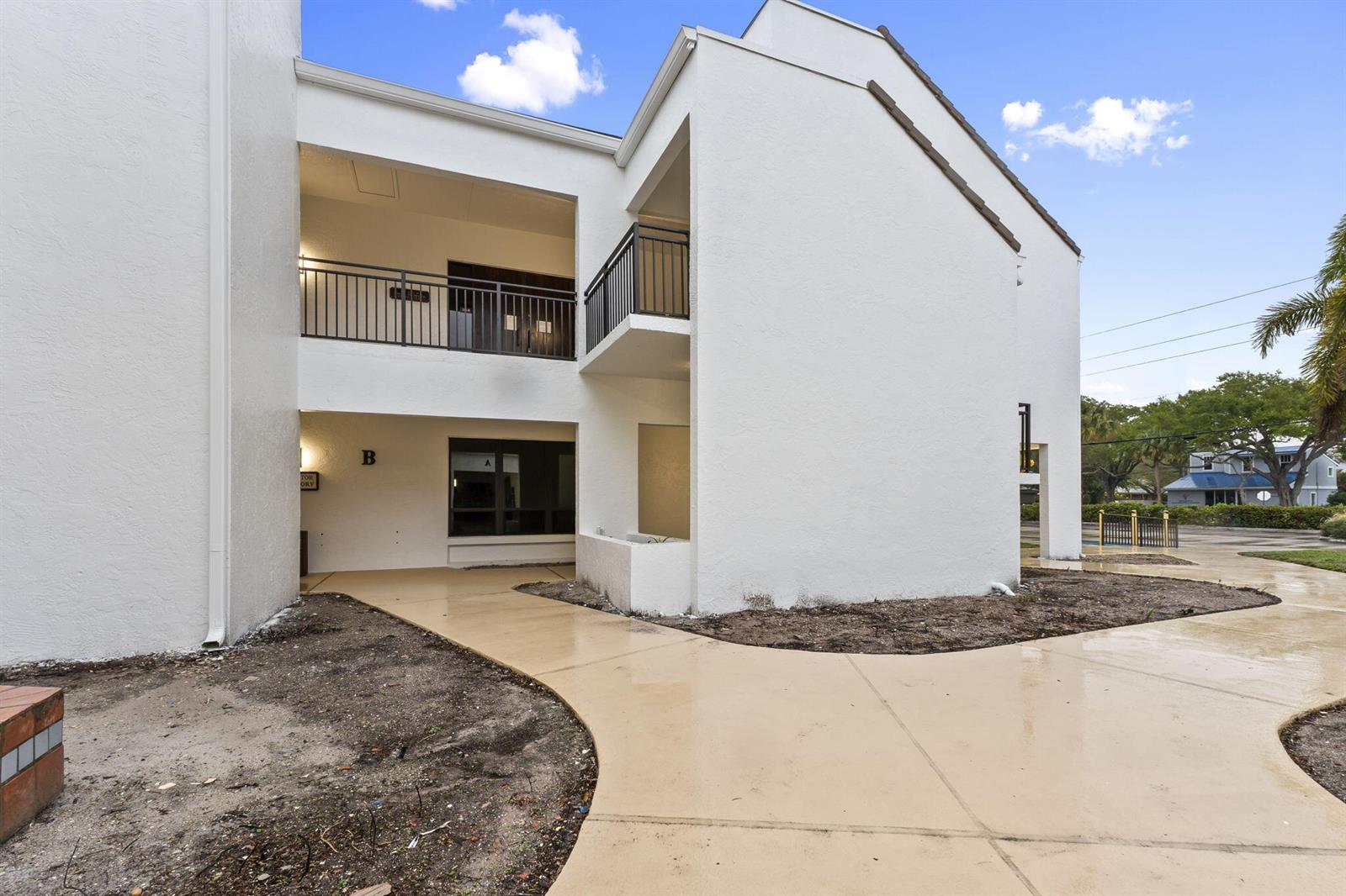 A two-story white stucco building features a concrete walkway and a second-floor balcony — 900 SE Ocean Boulevard # B212, Stuart FL 34994, STUART, FL