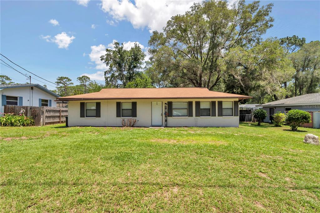 A single-story house with a tan exterior, dark shutters, and a brown shingled roof — 6389 E HOLLY STREET, INVERNESS, FL