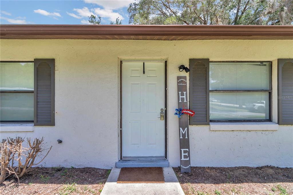 The exterior of a house features a white front door, windows with shutters, and a sign — 6389 E HOLLY STREET, INVERNESS, FL