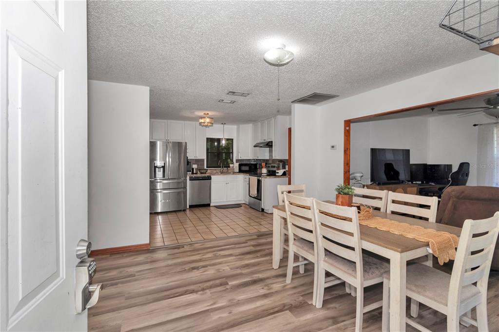 An open-concept kitchen and dining area with white cabinets, stainless appliances, and wood-look flooring — 6389 E HOLLY STREET, INVERNESS, FL