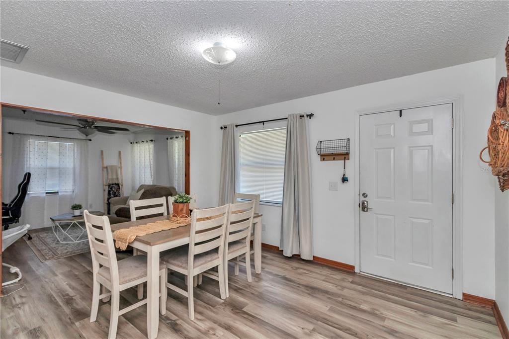 A dining area with a wooden table, white chairs, and wood-look flooring near an entrance — 6389 E HOLLY STREET, INVERNESS, FL