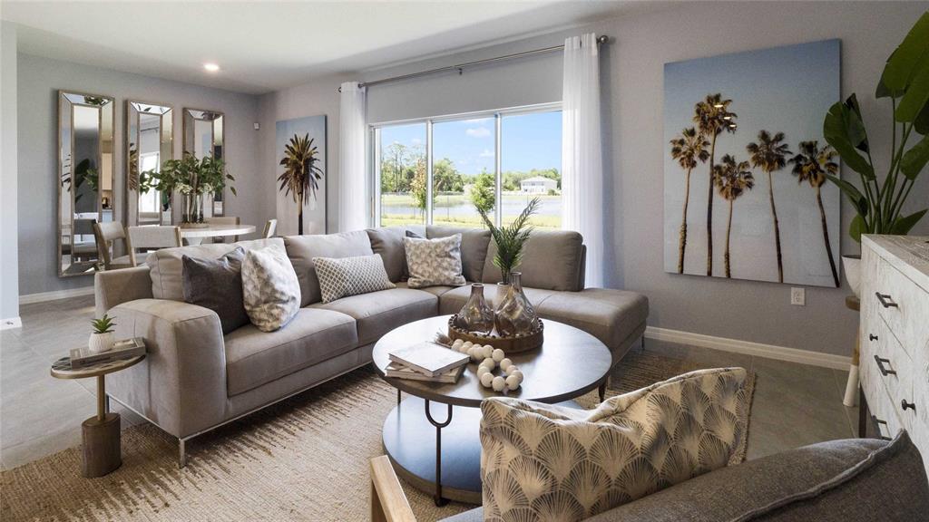 A living room features a gray sectional sofa, a round coffee table, and palm tree artwork — 2606 GOLDEN TROUT LANE, EDGEWATER, FL