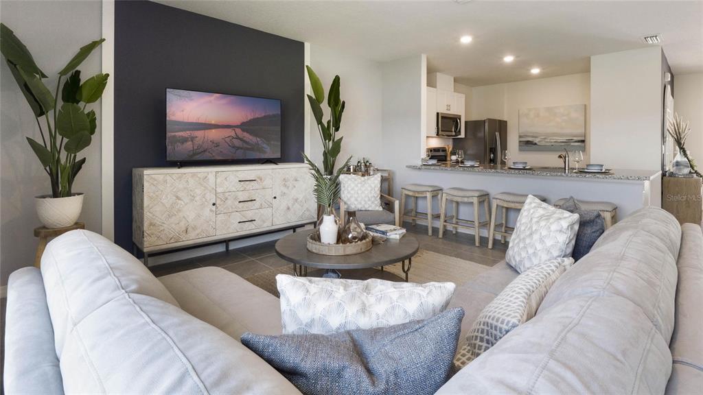 A living room with a dark accent wall, television, and an open kitchen with bar seating — 2606 GOLDEN TROUT LANE, EDGEWATER, FL