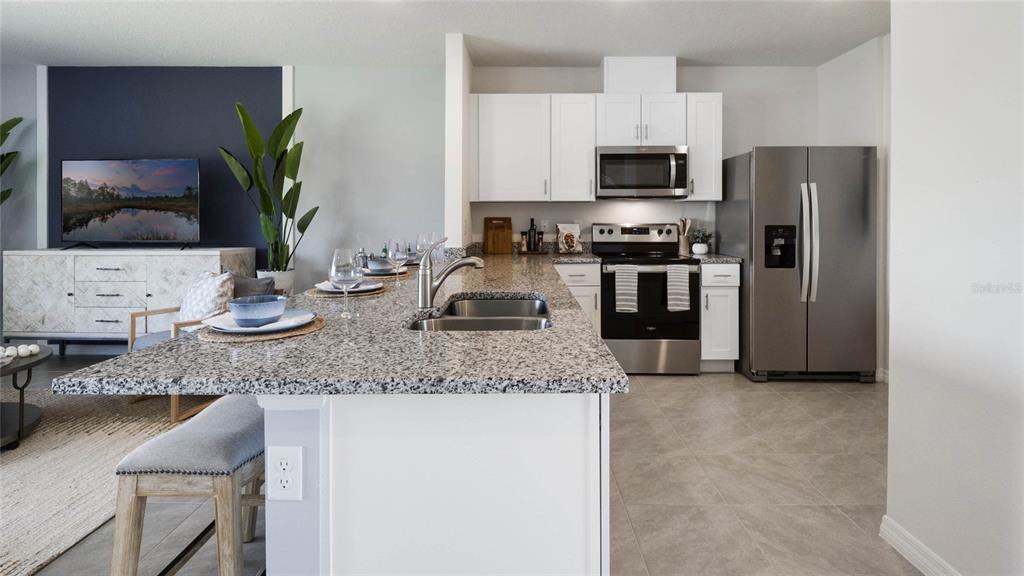 A kitchen features granite countertops, white cabinets, stainless steel appliances, and a breakfast bar — 2606 GOLDEN TROUT LANE, EDGEWATER, FL