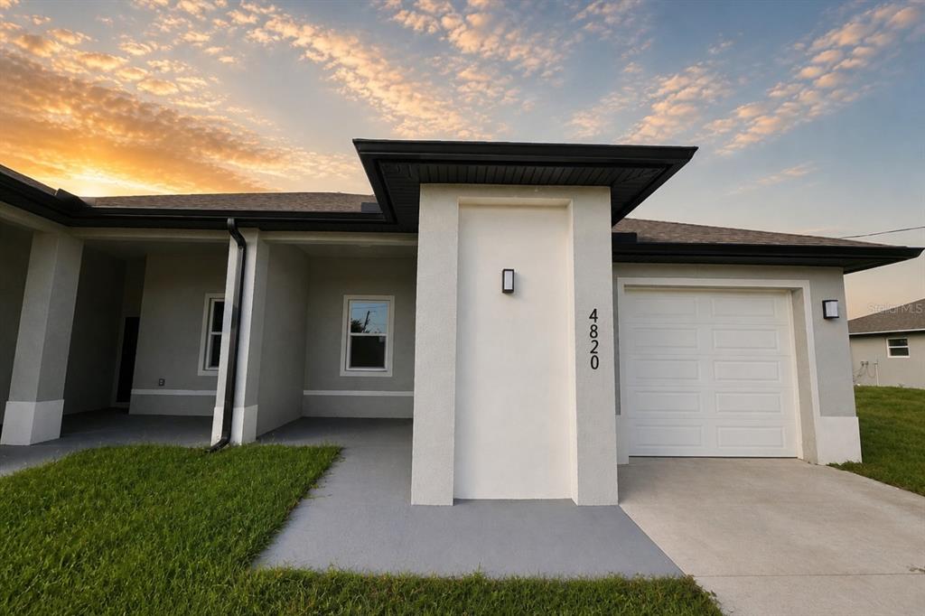A single-story house exterior features a white facade, a garage, and a covered entryway — 4820/4822 24TH STREET SW, LEHIGH ACRES, FL
