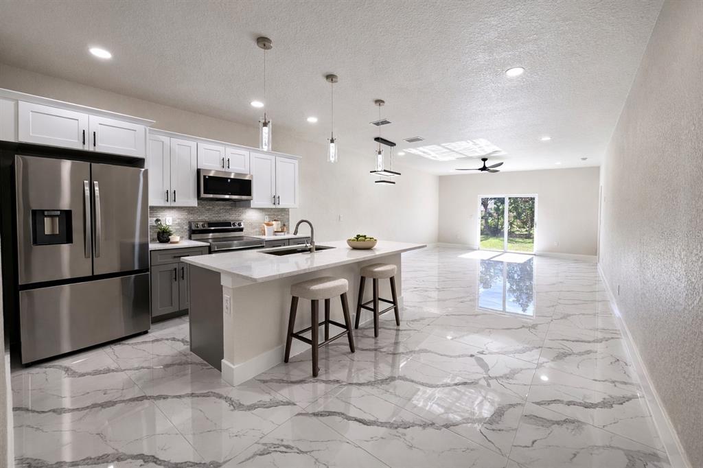 A modern kitchen with white cabinets, stainless steel appliances, and a marble-patterned tile floor — 4820/4822 24TH STREET SW, LEHIGH ACRES, FL