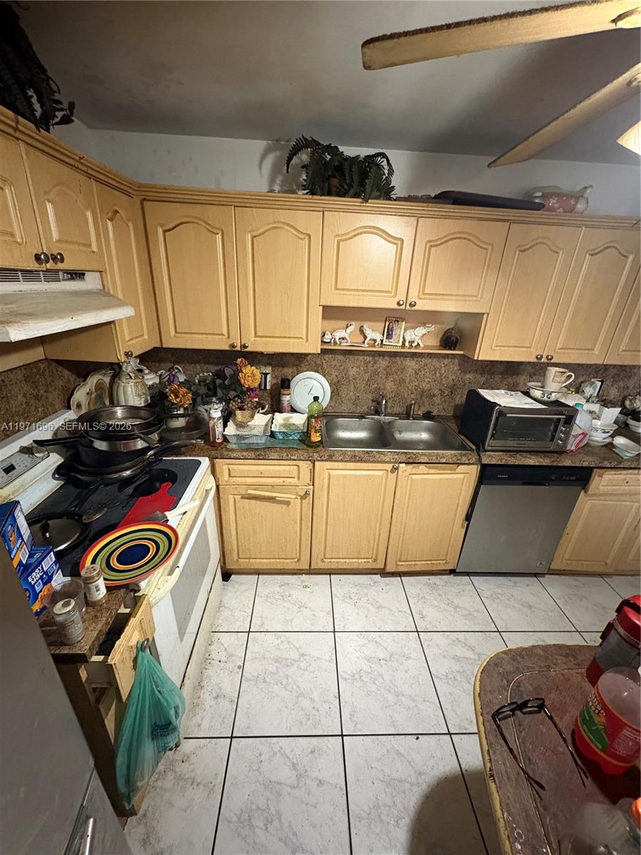 A kitchen features light wood cabinets, a double sink, and a white tile floor — 1401 NE 191st St # D204, Miami FL 33179, MIAMI, FL