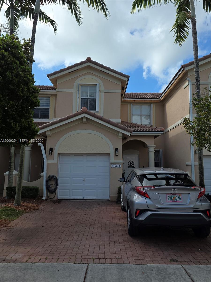 A two-story tan stucco townhouse with a single-car garage and a paved driveway — 12454 SW 123rd St, Miami FL 33186, MIAMI, FL