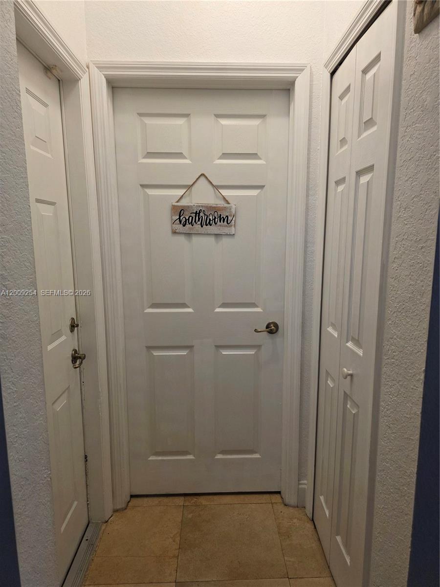 A white interior door with a bathroom sign is flanked by two white closet doors — 12454 SW 123rd St, Miami FL 33186, MIAMI, FL