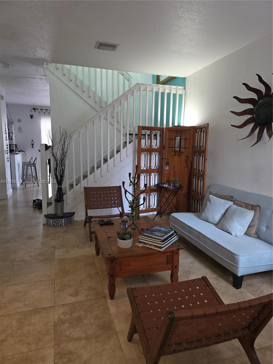 A living room features tile floors, a wooden coffee table, a light-colored sofa, and stairs — 12454 SW 123rd St, Miami FL 33186, MIAMI, FL