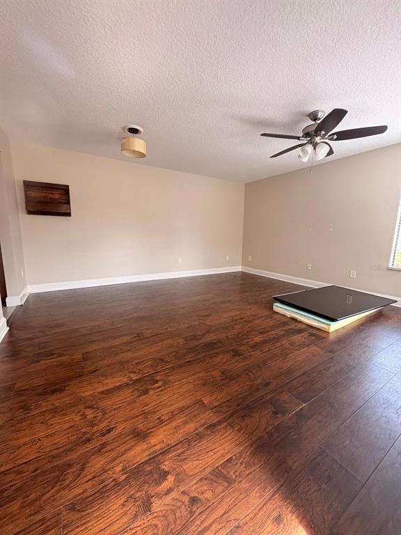 An empty room features dark wood flooring, a ceiling fan, and a light fixture — 2534 LEEWARD WAY, WINTER PARK, FL