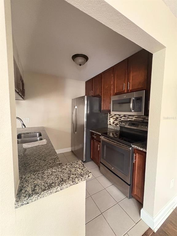 A kitchen features dark wood cabinets, granite countertops, stainless steel appliances, and tiled flooring — 2534 LEEWARD WAY, WINTER PARK, FL