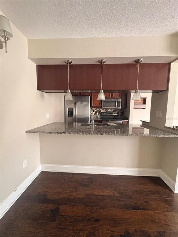 A kitchen with a granite breakfast bar, pendant lighting, and dark wood flooring — 2534 LEEWARD WAY, WINTER PARK, FL