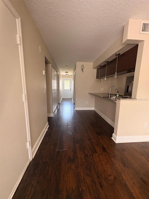 A hallway with dark wood floors leads to an exterior door past a kitchen counter — 2534 LEEWARD WAY, WINTER PARK, FL