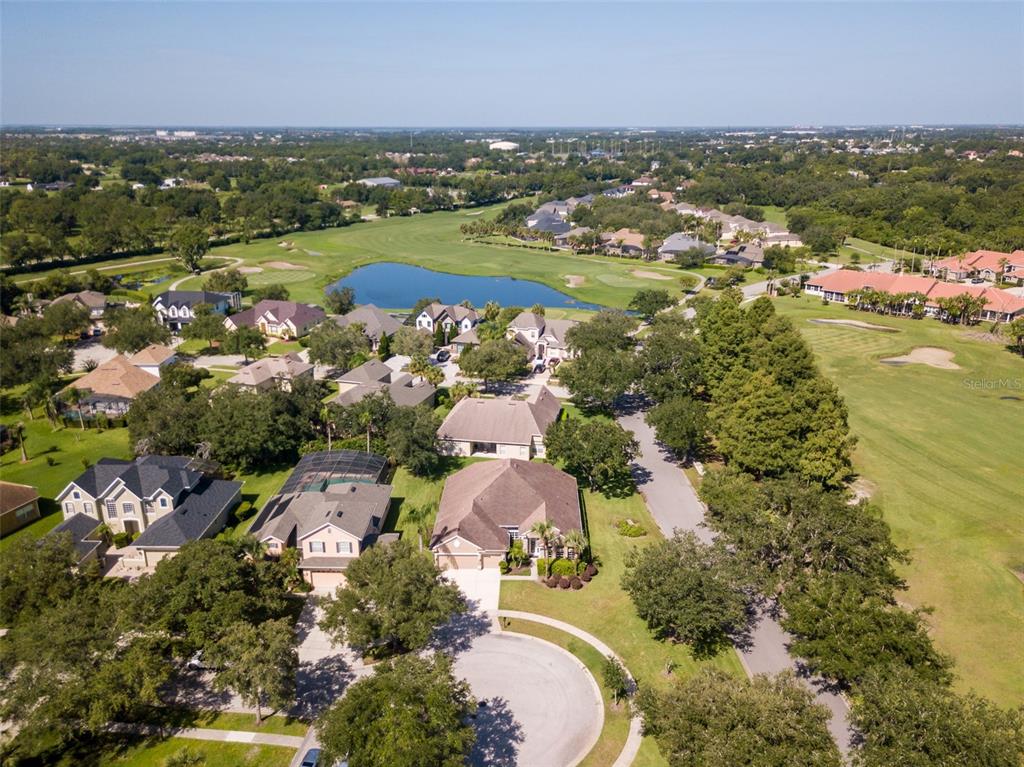 An aerial view shows a suburban neighborhood with houses surrounding a pond and golf course — 1733 BRIDGETS COURT, KISSIMMEE, FL