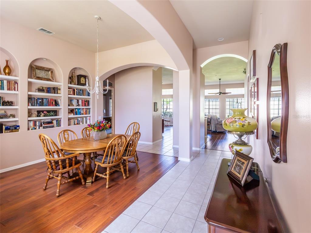 A dining room with built-in arched bookshelves, a wooden table, and tile flooring — 1733 BRIDGETS COURT, KISSIMMEE, FL