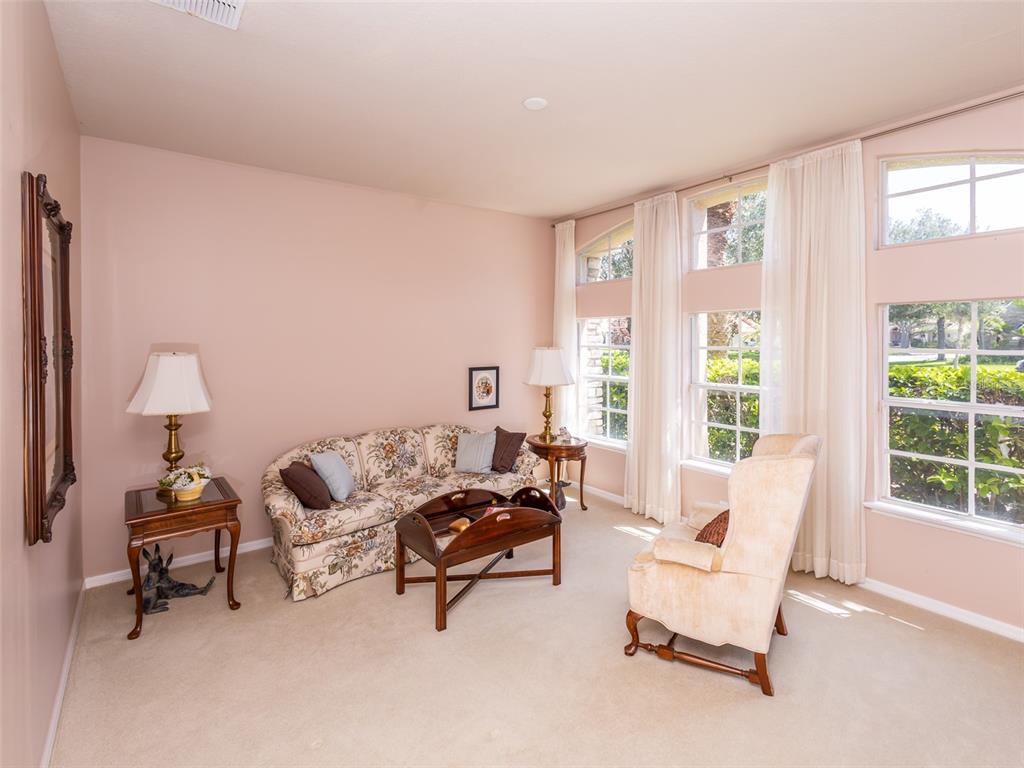 A living room features a floral sofa, a beige armchair, and large windows with curtains — 1733 BRIDGETS COURT, KISSIMMEE, FL