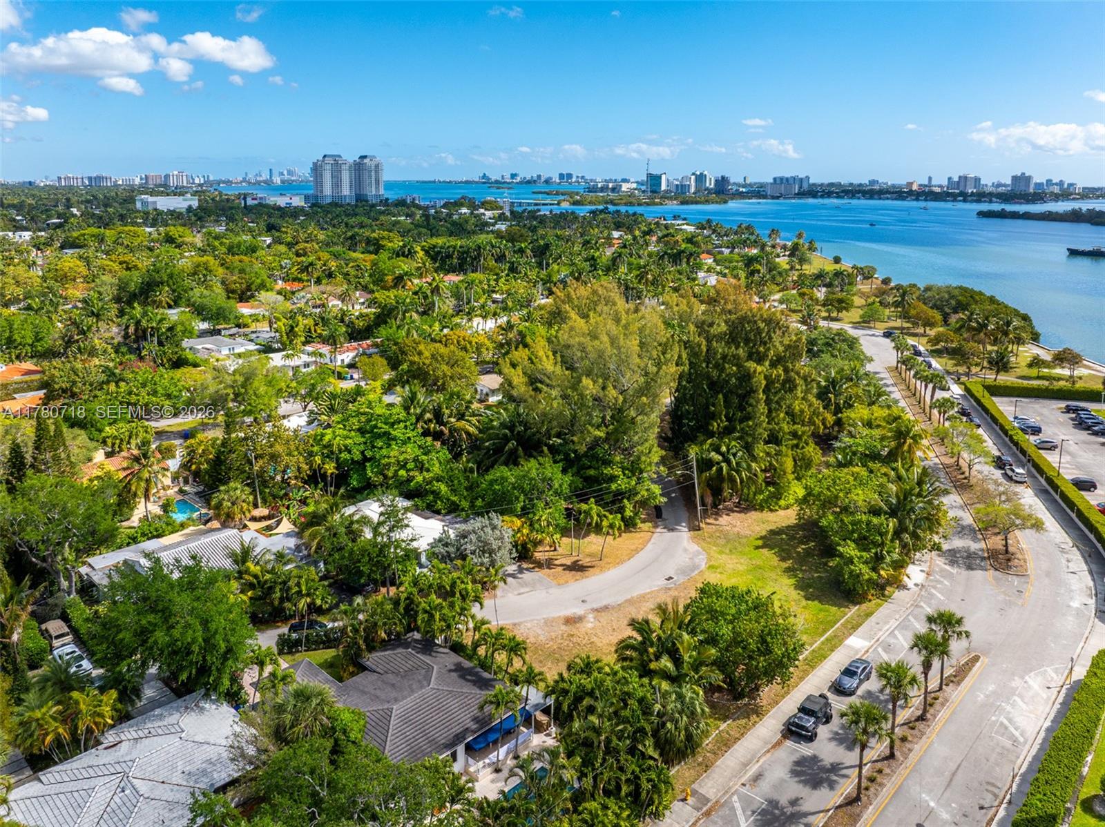 An aerial view shows a residential neighborhood with lush trees, a road, and waterfront views — 890 NE 70th St, Miami FL 33138, MIAMI, FL