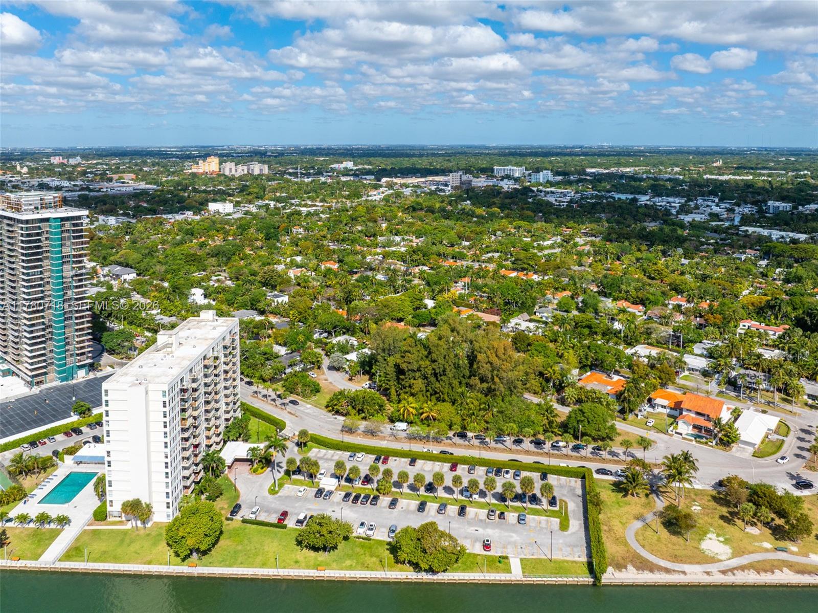 An aerial view shows two high-rise apartment buildings next to a parking lot and waterfront — 890 NE 70th St, Miami FL 33138, MIAMI, FL