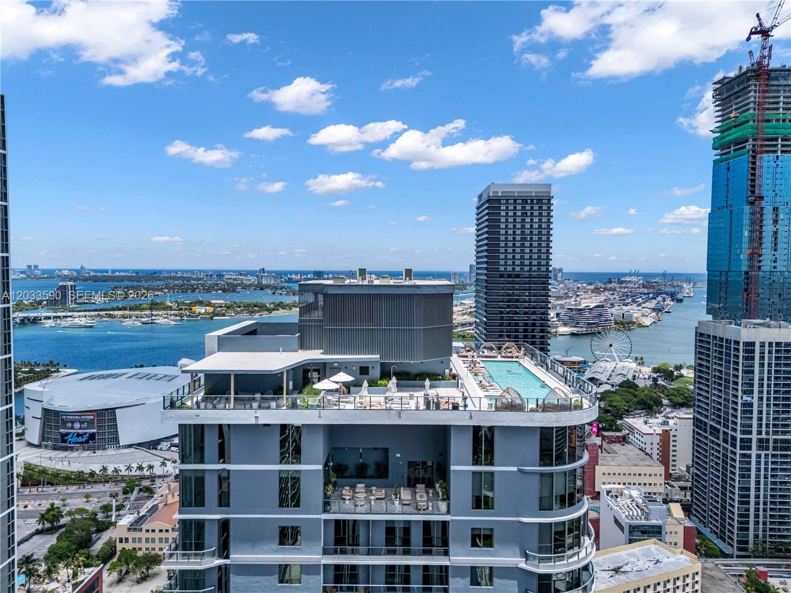 An aerial view shows a high-rise building rooftop with a swimming pool and lounge area — 121 NE 5th St # 1400, Miami FL 33132, MIAMI, FL