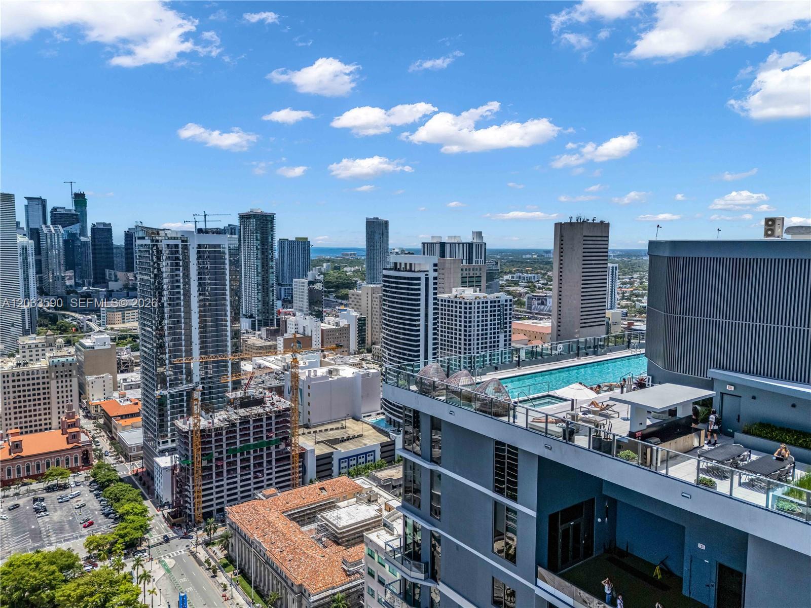 A high-angle view shows a rooftop pool deck overlooking a dense urban skyline — 121 NE 5th St # 1400, Miami FL 33132, MIAMI, FL