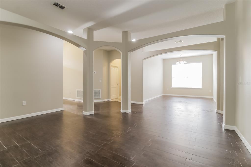 An interior view of a room with dark tile flooring and arched architectural columns — 2114 THE OAKS BOULEVARD, KISSIMMEE, FL