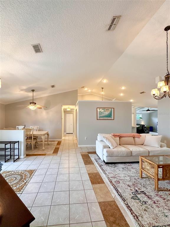 An open-concept living and dining area features vaulted ceilings, tile flooring, and a neutral color palette — 9233 IRONDALE LANE, HUDSON, FL