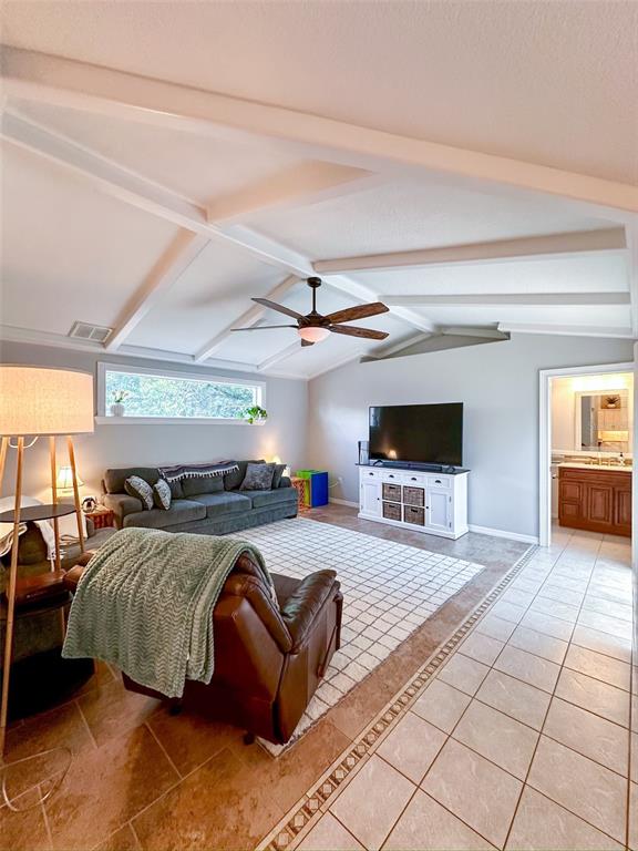 A living room features a vaulted ceiling with exposed beams, tile flooring, and a ceiling fan — 9233 IRONDALE LANE, HUDSON, FL