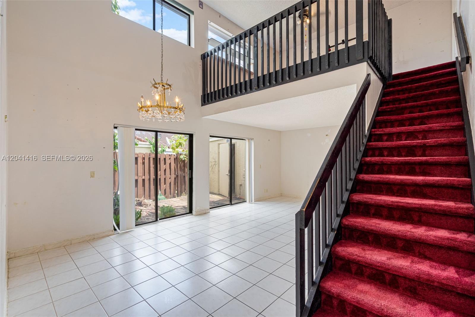 A living room with white tile floors, a red carpeted staircase, and a crystal chandelier — 6233 NW 170th Ter, Miami FL 33015, MIAMI, FL