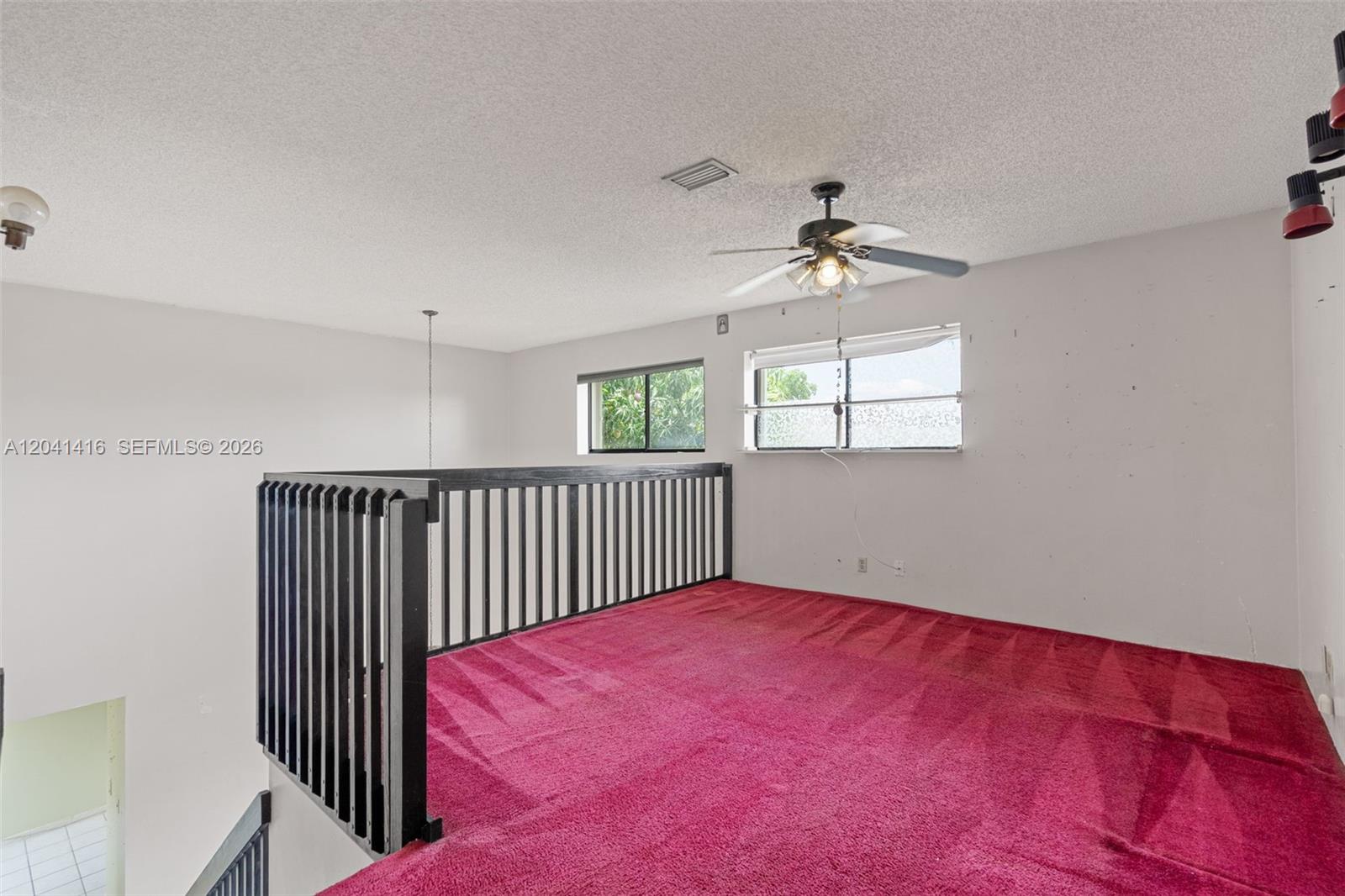 An indoor loft area features a black railing, red carpeting, and a ceiling fan — 6233 NW 170th Ter, Miami FL 33015, MIAMI, FL
