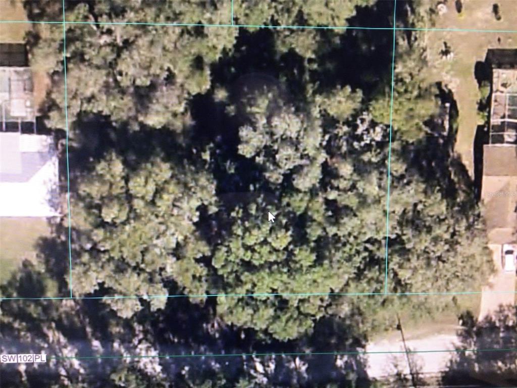 An aerial view shows a wooded, rectangular residential lot bordered by neighboring houses and streets — 0 SW 102 PLACE, DUNNELLON, FL