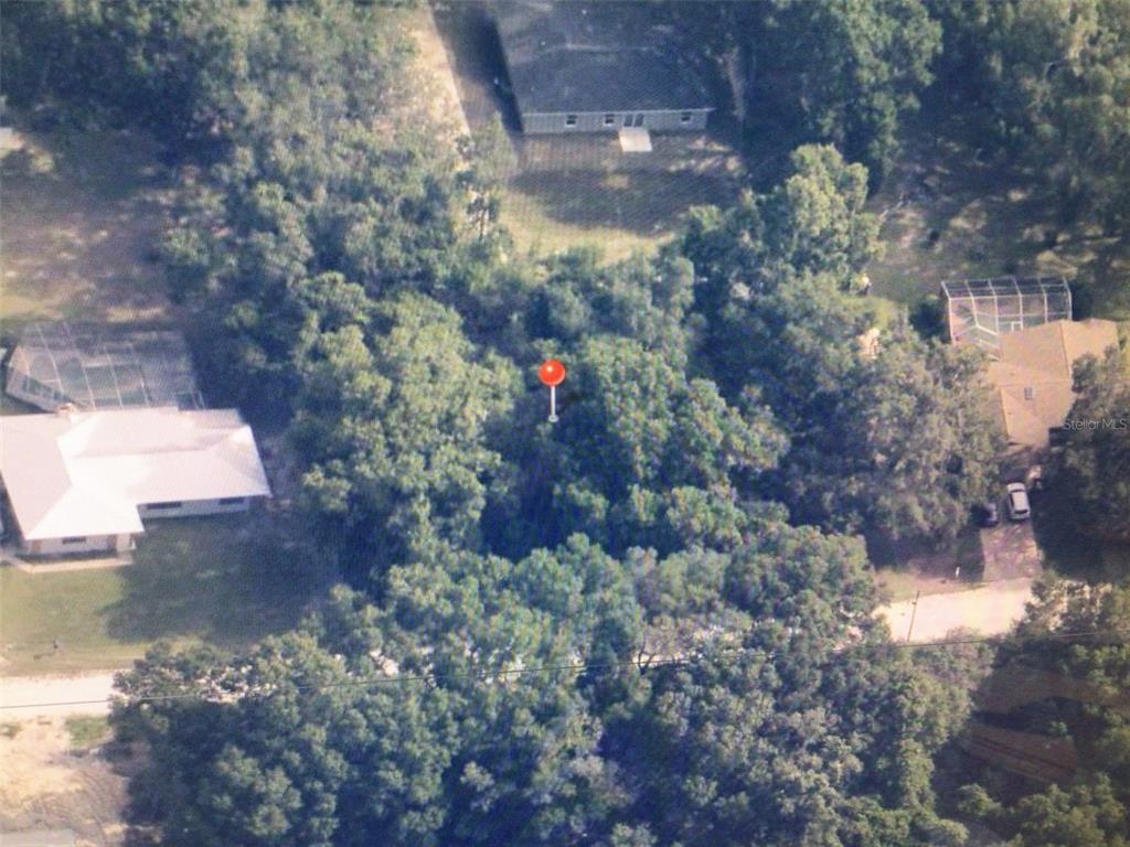 This aerial view shows a wooded residential lot marked with a red pin — 0 SW 102 PLACE, DUNNELLON, FL