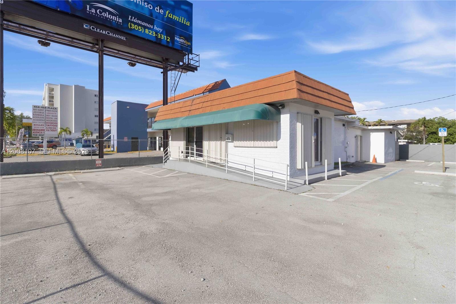 A single-story commercial building with a green awning, wheelchair ramp, and adjacent parking lot — 470 NW 22nd Ave, Miami FL 33125, MIAMI, FL
