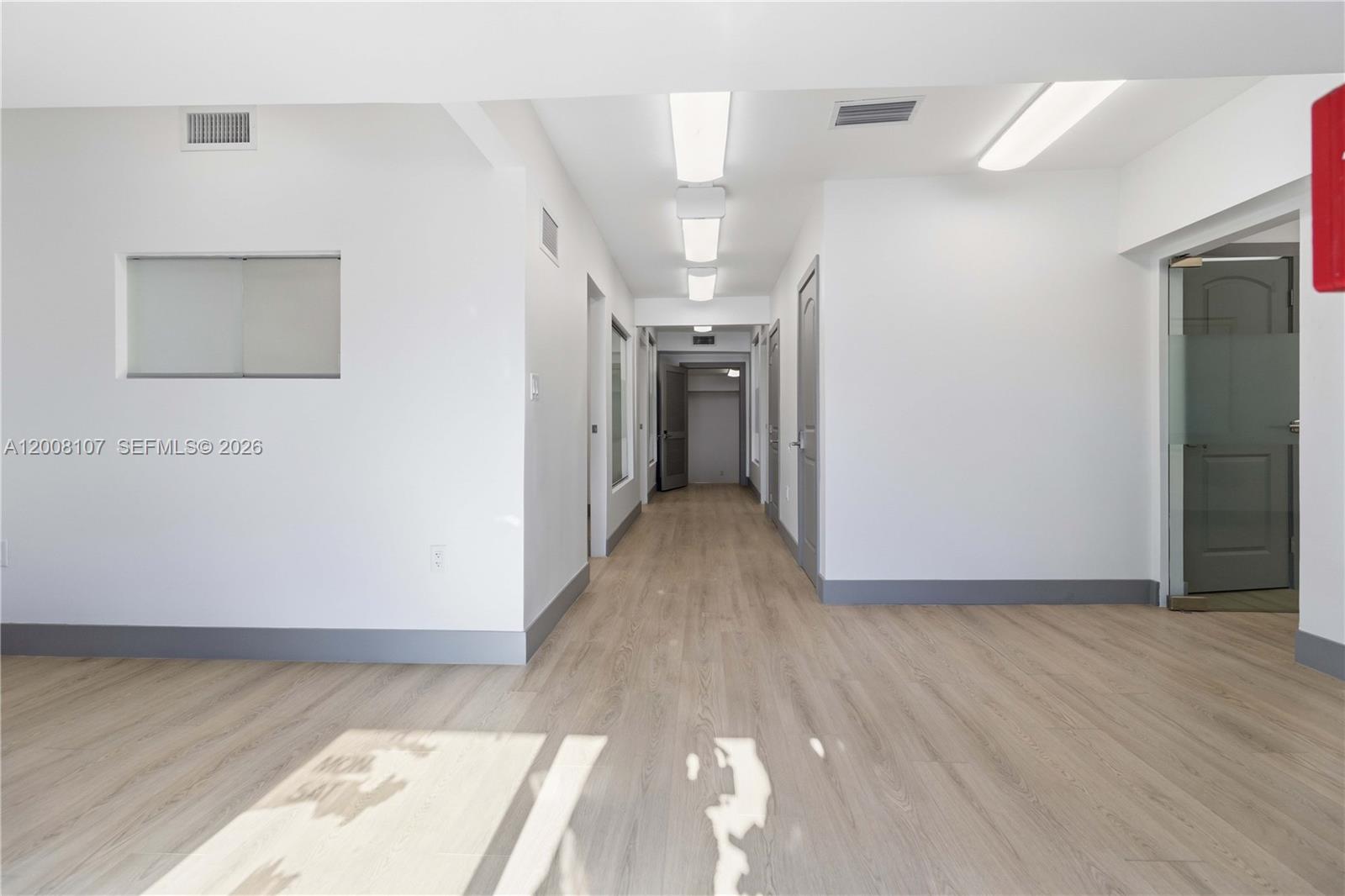 A bright hallway with light wood-look flooring, white walls, and several interior doors — 470 NW 22nd Ave, Miami FL 33125, MIAMI, FL