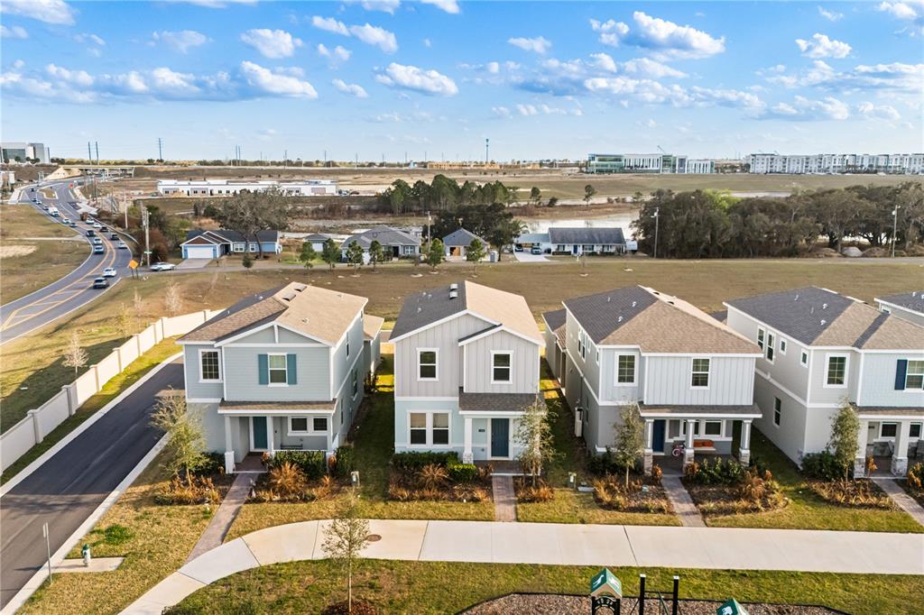 An aerial view shows a row of modern, light-colored suburban houses near a road — 16848 HAMLIN VISTA ALLEY, WINTER GARDEN, FL