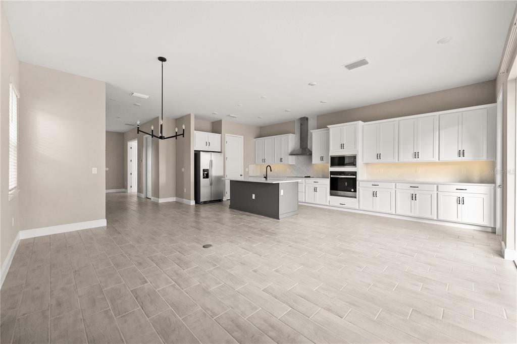 A modern kitchen features white cabinetry, a gray island, and light wood-look tile flooring — 16848 HAMLIN VISTA ALLEY, WINTER GARDEN, FL