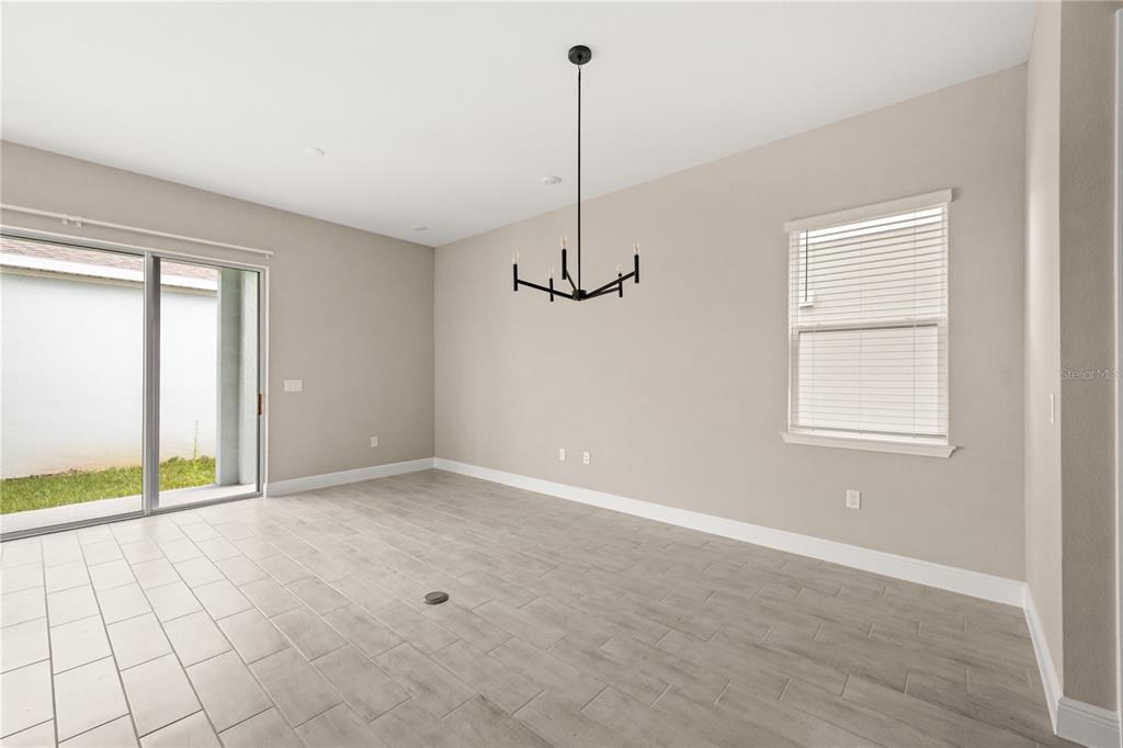 A dining area features light-colored tile flooring, a modern chandelier, and a sliding glass door — 16848 HAMLIN VISTA ALLEY, WINTER GARDEN, FL